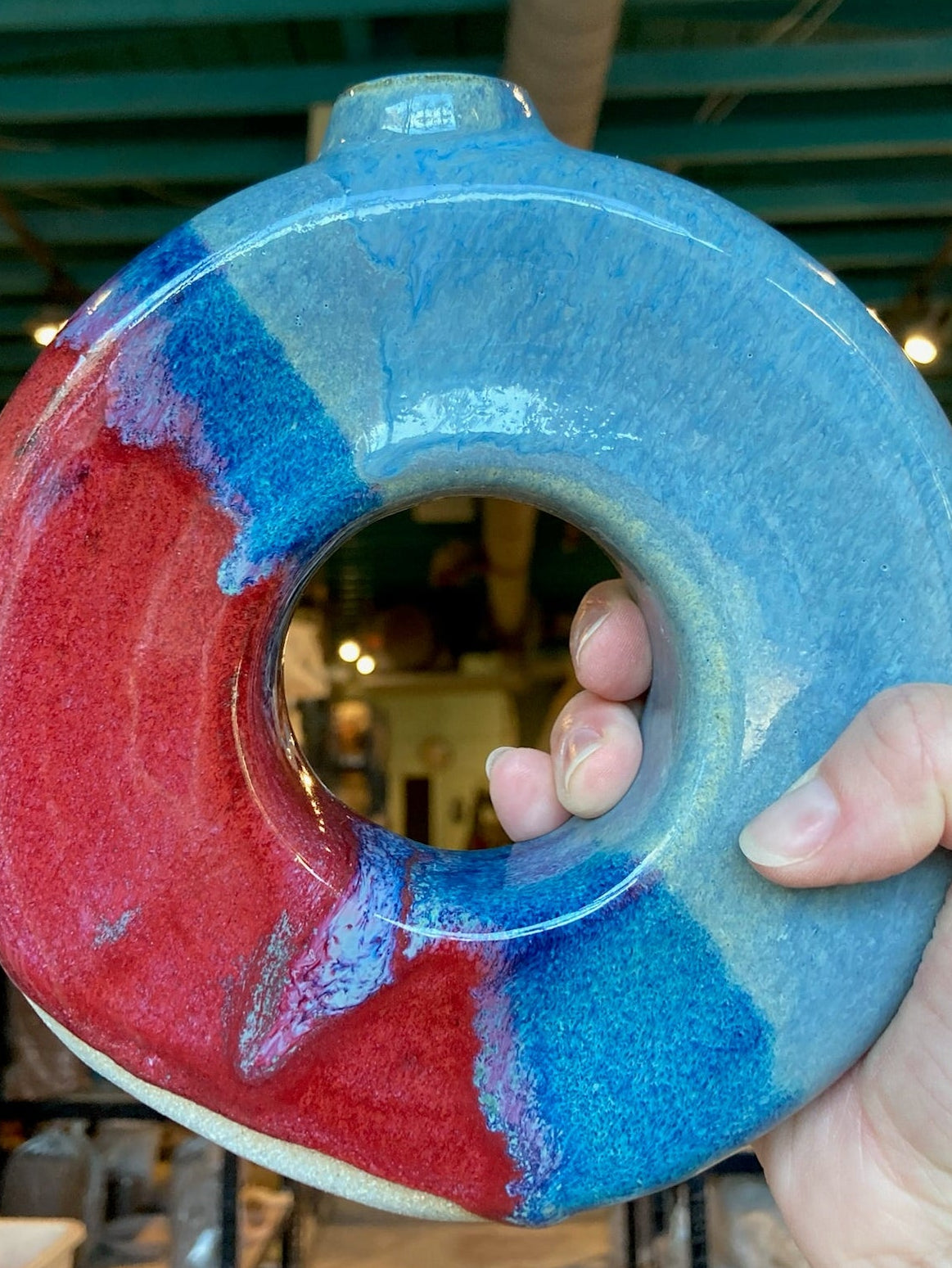 Blue and red circular object held in a hand with a blurred indoor background
