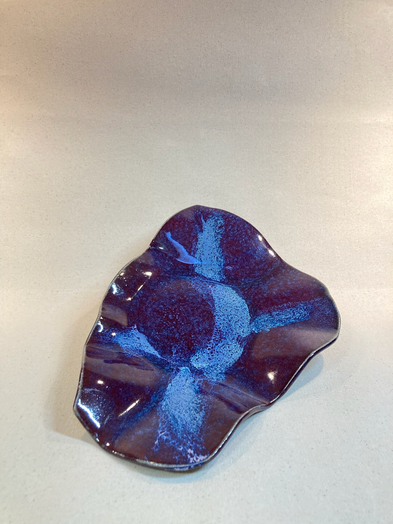 Decorative glass piece with blue and purple design on a light gray background